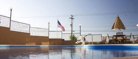 A swimming pool with a flag, a lifeguard stand, and a lounge chair.