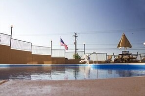 A swimming pool with a flag, a lifeguard stand, and a lounge chair.