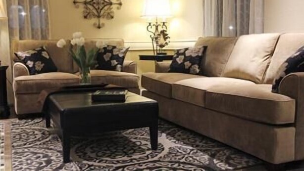Ein Wohnzimmer mit zwei Sofas, einem Couchtisch, einer Lampe und einem Wandbild.