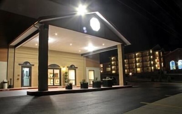 A hotel with a covered outdoor area, a reception desk, and a building with multiple windows.