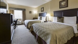 Ein Hotelzimmer mit zwei Betten, einem Schreibtisch und einer Kommode.