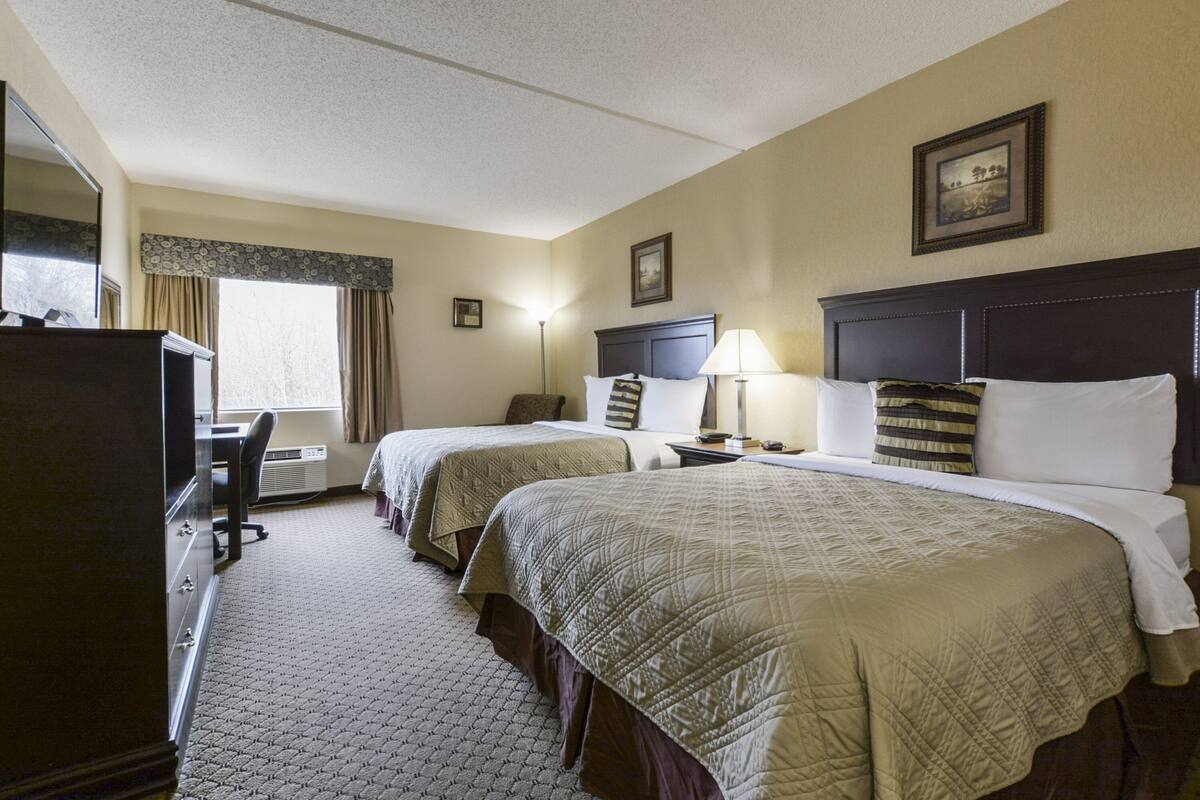 A hotel room with two beds, a desk, and a dresser.