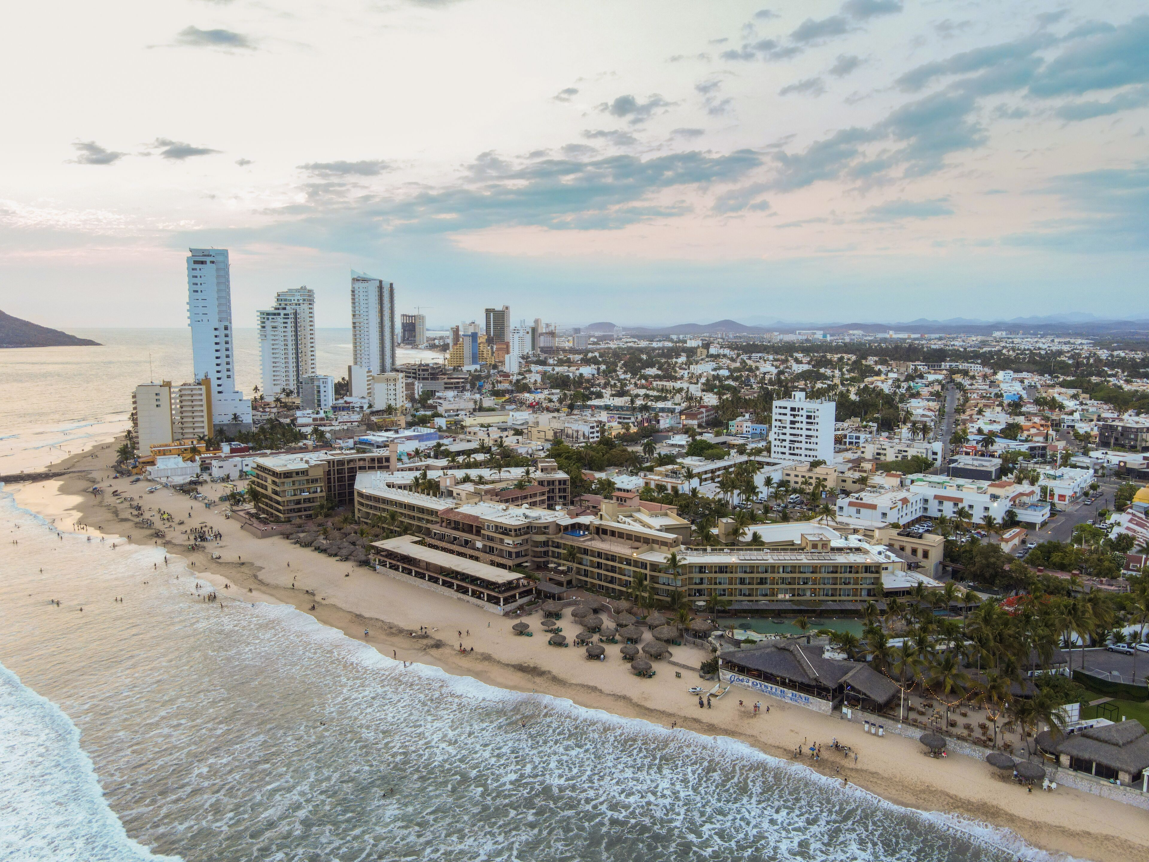 A coastal cityscape with high-rise buildings, a beach, and a resort area.