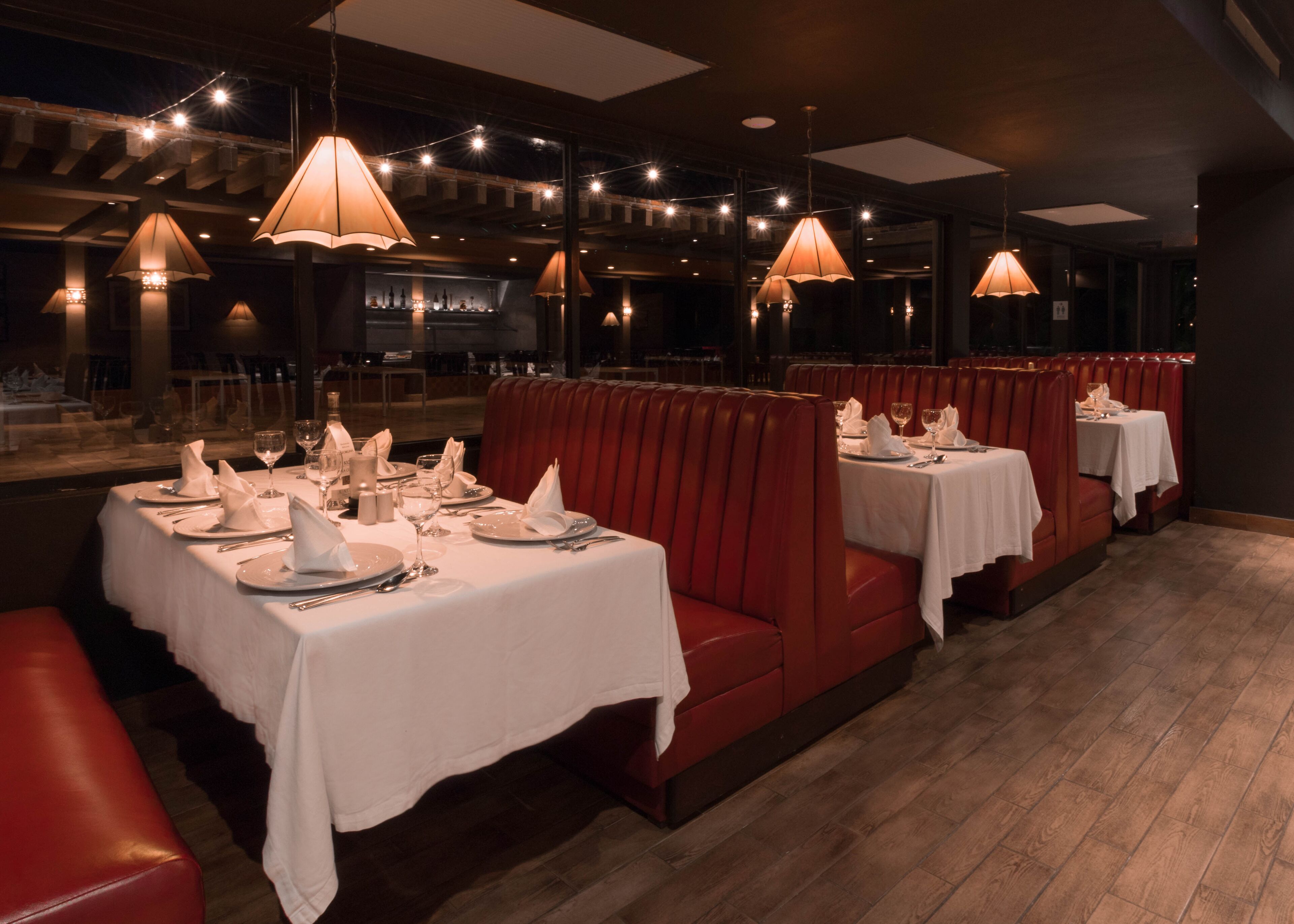A restaurant with booths and tables, string lights, and a bar area.