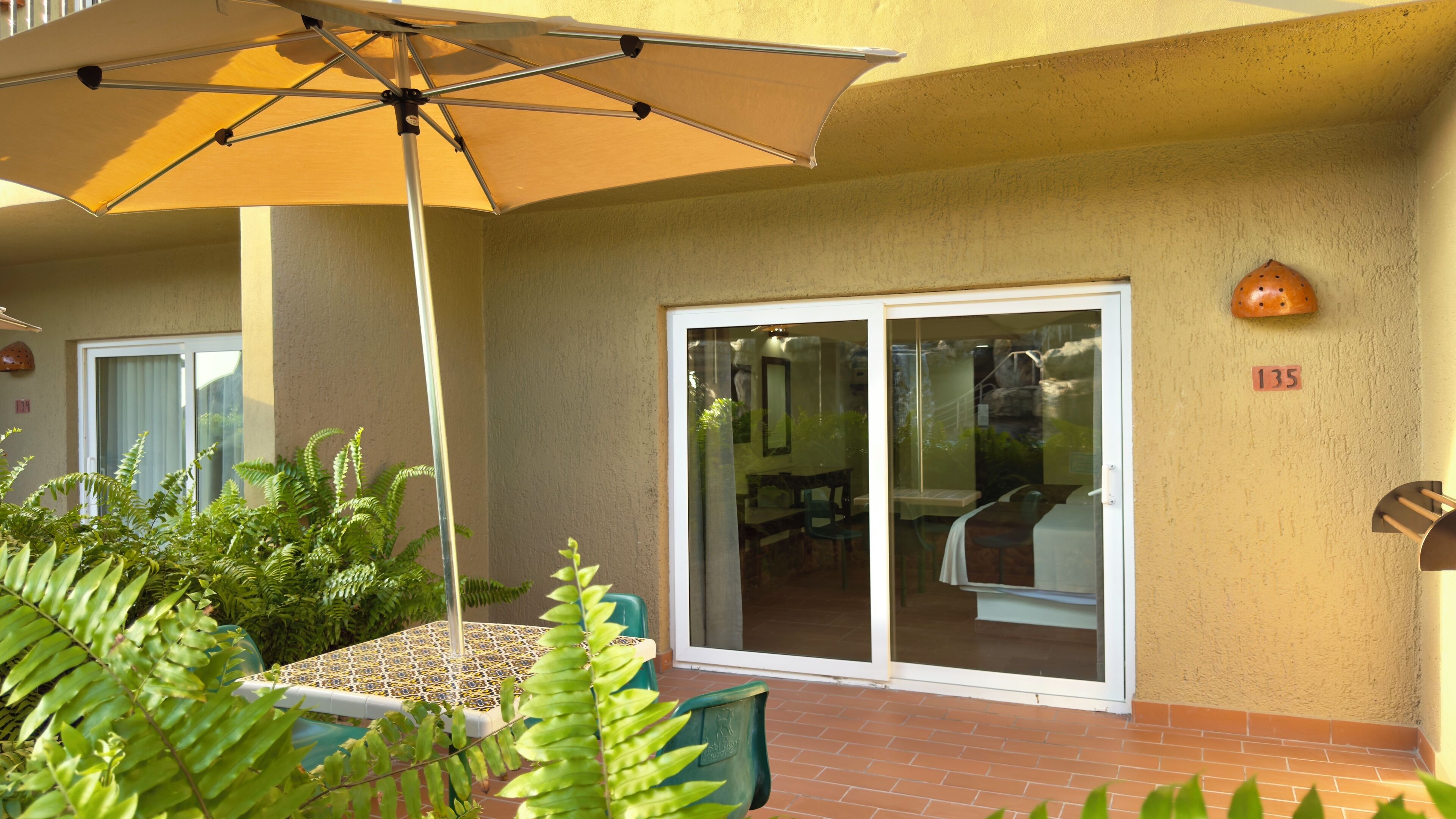 A patio area with a table and chairs, a large umbrella, and a sliding glass door leading to an indoor space.