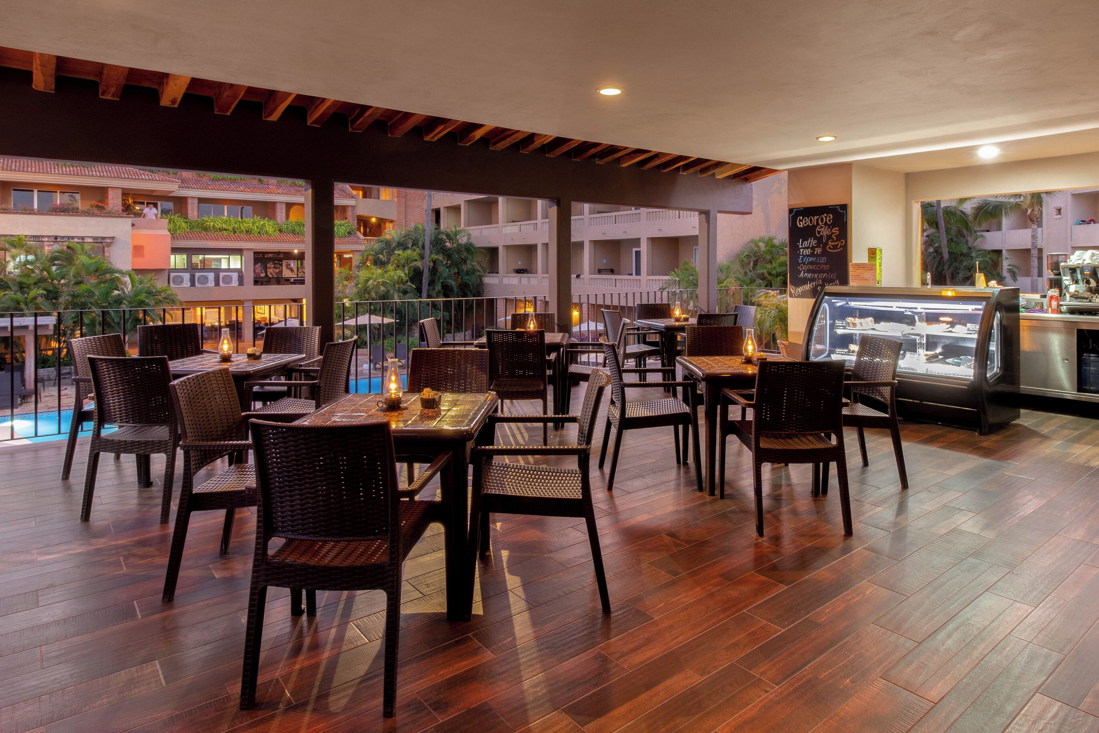 An outdoor dining area with wicker furniture and a view of the pool and buildings.
