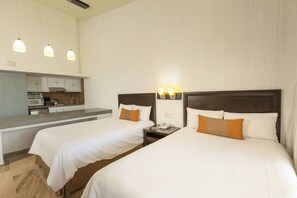 Una habitación de hotel con dos camas, kitchenette y baño.