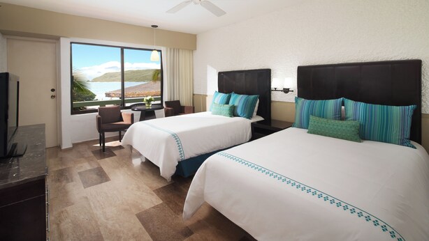 A hotel room with two beds, a ceiling fan, a view of the ocean, a desk, and a chair. - El Cid Castilla Beach Hotel (Mazatlán)