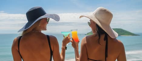 Two individuals at a seaside location, each holding a drink.