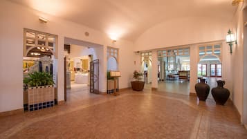 Um hall amplo com piso ladrilhado, escadaria e área de recepção.