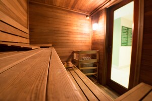 Un sauna con bancos de madera y una pequeña mesa de madera.