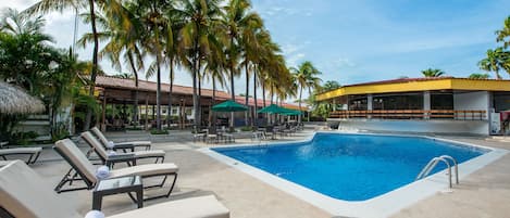 Un área de piscina con sillas de descanso y palmeras.