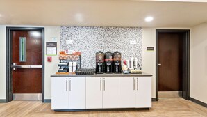 A reception area with a coffee station, a fire extinguisher, and a sign indicating the exit route. - Extended Stay America Premier Suites - Union City - Dyer St. (Union City)