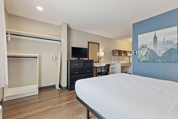 A hotel room with a bed, a desk, a chair, a TV, a wardrobe, and a painting on the wall. - Extended Stay America Premier Suites - Union City - Dyer St. (Union City)