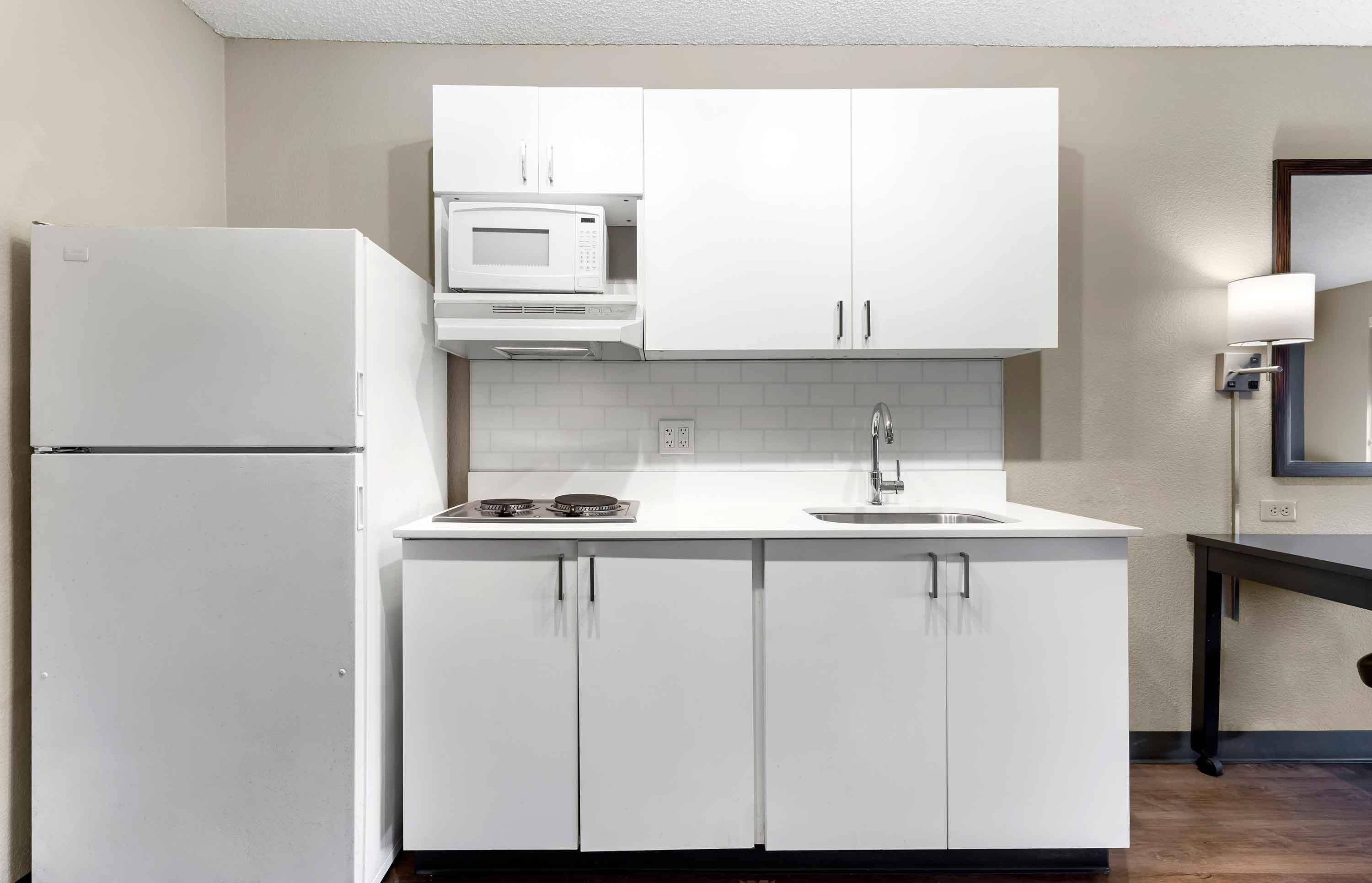 Una cocina moderna con armarios blancos, microondas integrado, estufa y lavaplatos.
