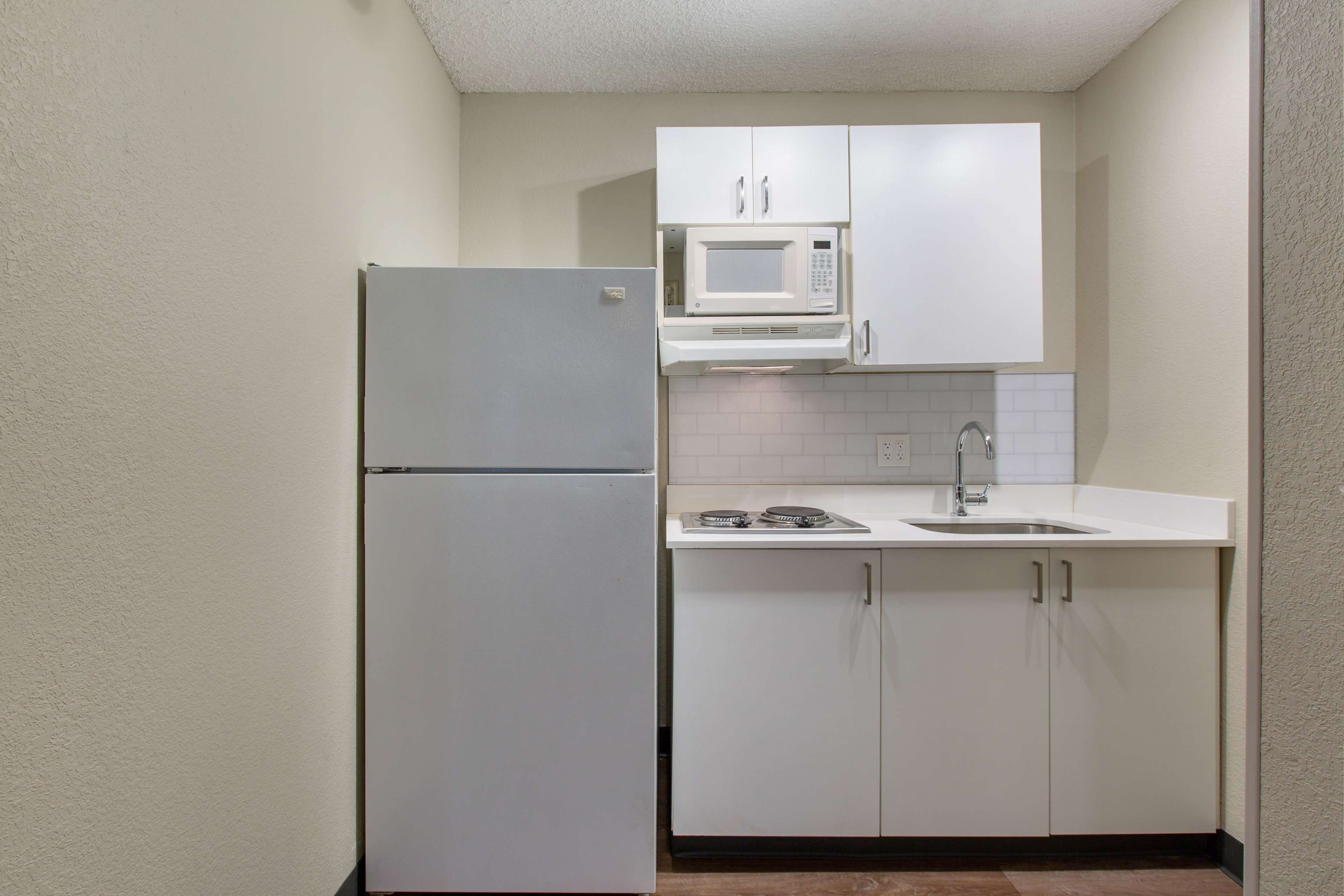 Cocina compacta con un refrigerador blanco, un microondas y un lavamanos.