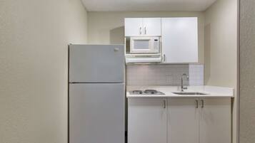 Cocina compacta con un refrigerador blanco, un microondas y un lavamanos.