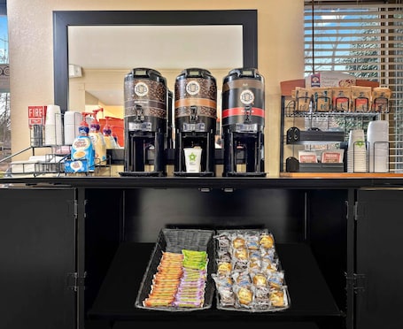 A coffee station with two coffee makers, a tray of pastries, and a display of coffee pods.
