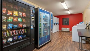 A vending area with snack and drink machines, a red wall, and a white counter.