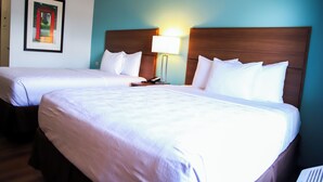 A hotel room with two beds, a nightstand, a lamp, and a framed picture on the wall. - MainStay Suites Chicago Hillside (Hillside)