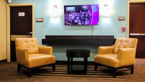 A lobby with two leather armchairs, a small black table, a flat-screen TV on the wall, and a sign indicating a staff-only room. - MainStay Suites Chicago Hillside (Hillside)