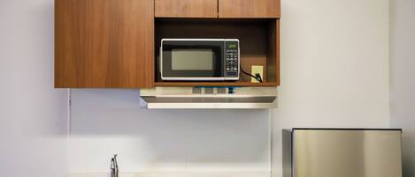 A kitchen with a microwave, stainless steel sink, and a refrigerator.