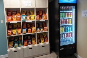 A snack vending machine and a shelf with various chips and snacks. - MainStay Suites Chicago Hillside (Hillside)