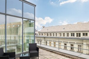 Un edificio moderno con ampie finestre e un balcone con poltrone in vimini.