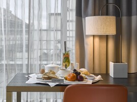 Uma mesa de café da manhã com uma chaleira, xícara, torradas, frutas e uma placa com a inscrição 'Bon appétit'.