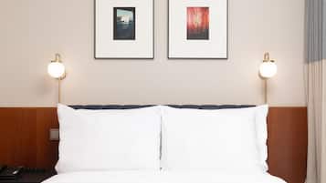 Una habitación de hotel con una cama, dos cuadros en la pared y lámparas de noche.