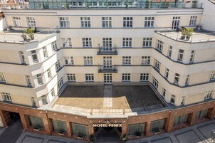 Un hotel a più piani con un cortile interno, balconi e un ingresso ben visibile.