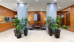 Un hall d’entrée moderne avec un comptoir d’accueil, un espace salon et des plantes en pot.