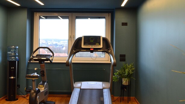 A gym with a treadmill, stationary bikes, and a water dispenser. - Seaside Residenz Hotel Chemnitz (Chemnitz)