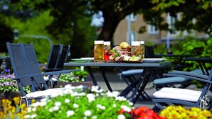 An outdoor dining area with a table set for two, featuring a variety of food and drinks. - Seaside Residenz Hotel Chemnitz (Chemnitz)