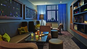 A modern lounge area with seating, a coffee table with drinks, and a bookshelf. - Seaside Residenz Hotel Chemnitz (Chemnitz)