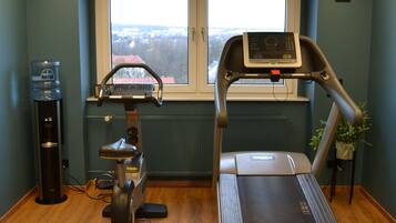Ein Fitnessraum mit Laufband, Wasserspender und Ergometer.