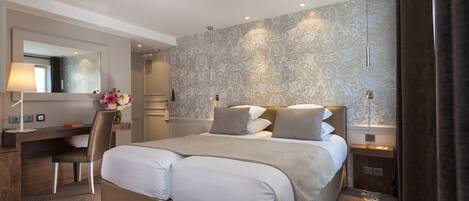 A modern hotel room with a large bed, a desk, and a chair.