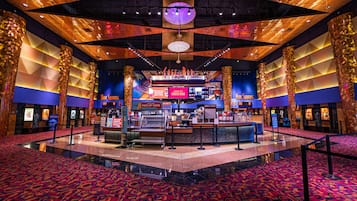 A hotel lobby with a central bar area, a patterned carpet, and a modern ceiling design.