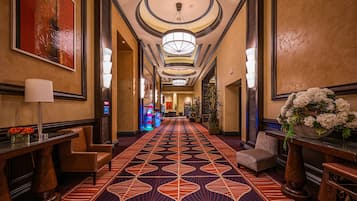 Un hall d’hôtel doté d’un tapis à motifs, de meubles en bois et d’un grand lustre.