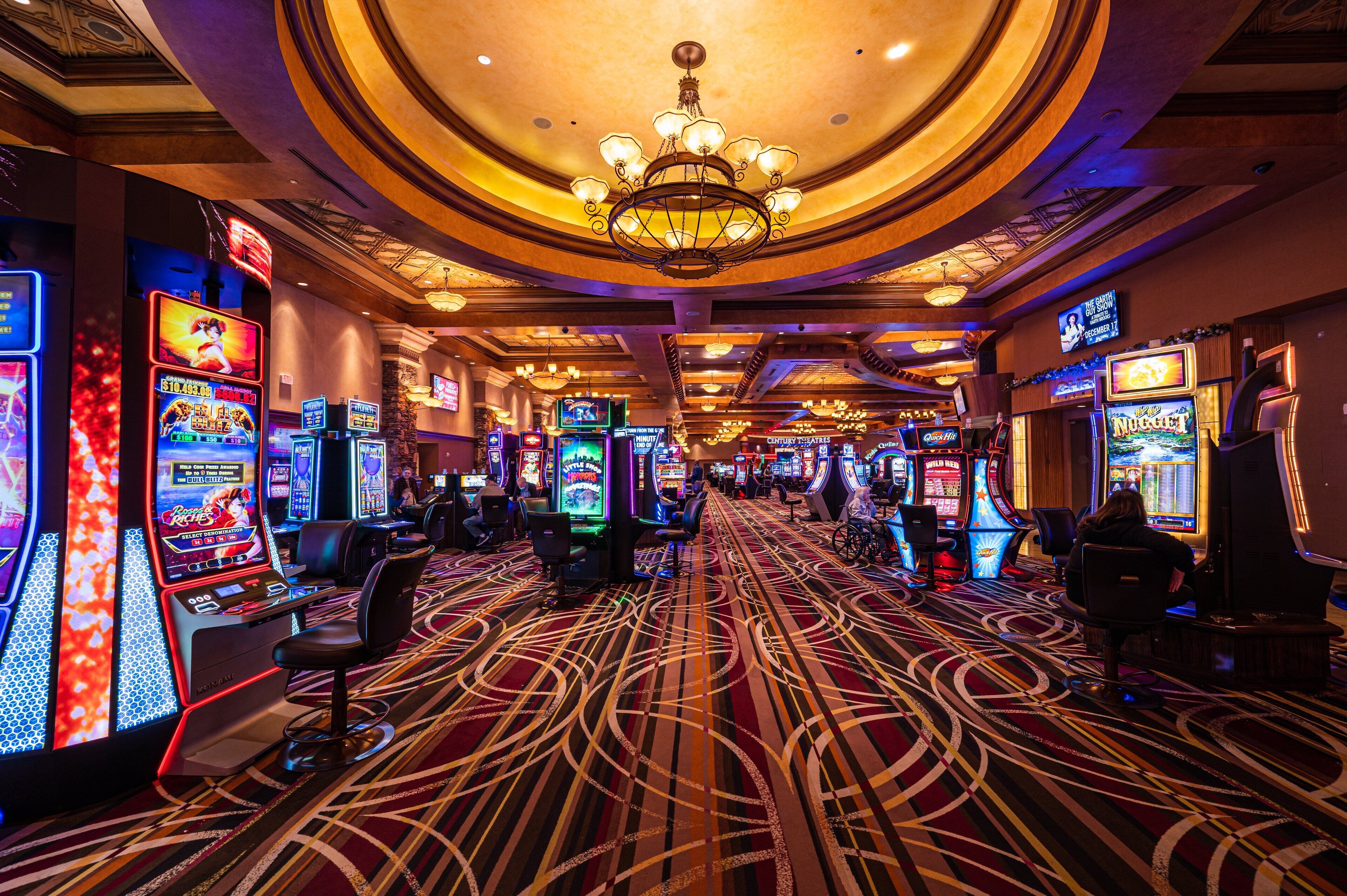 Un casino con máquinas tragamonedas, una araña y una alfombra estampada.