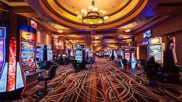 Un casino con máquinas tragamonedas, una araña y una alfombra estampada.