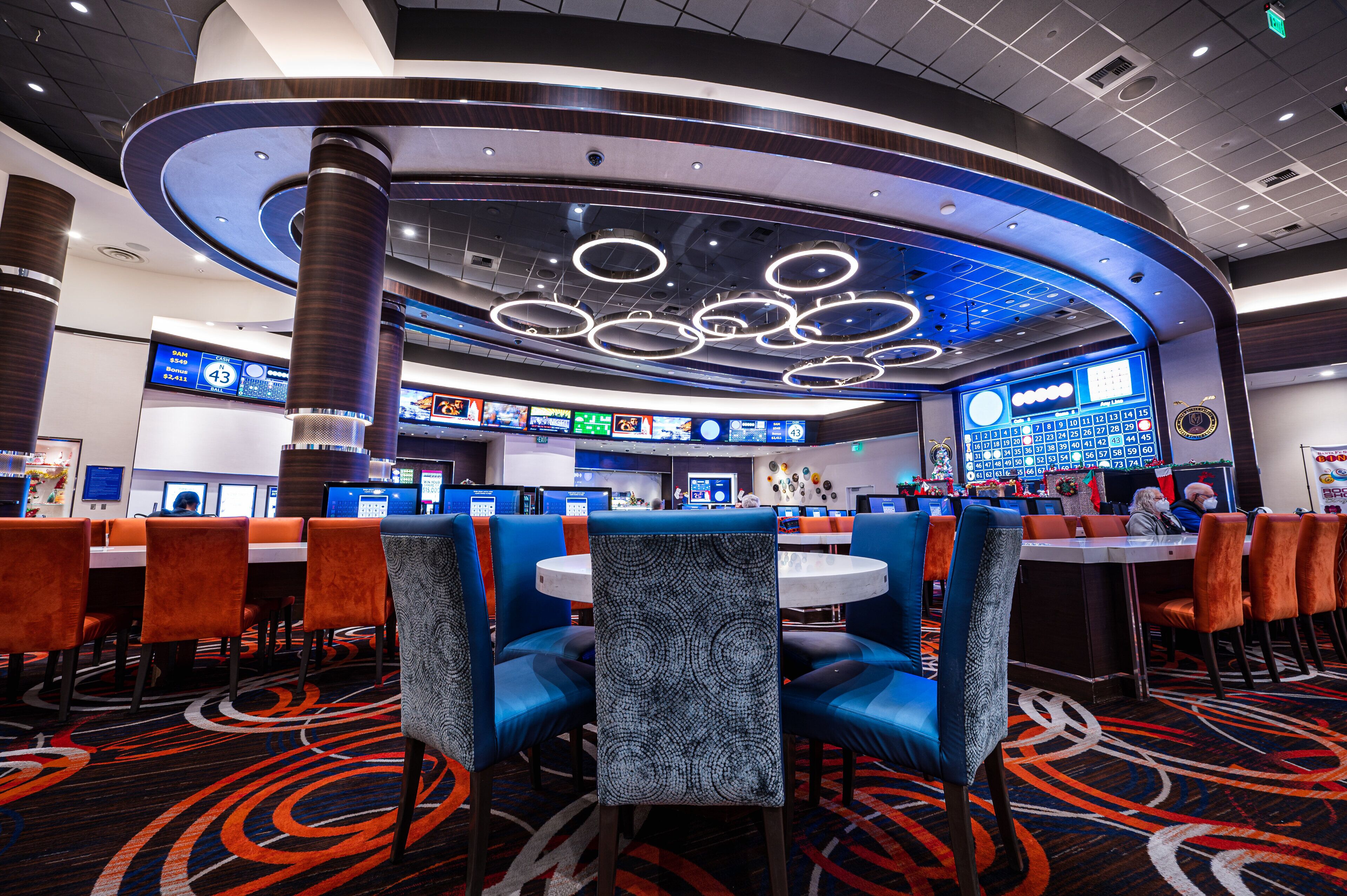 A modern hotel lobby with a curved reception desk, multiple seating areas, and a large digital display.