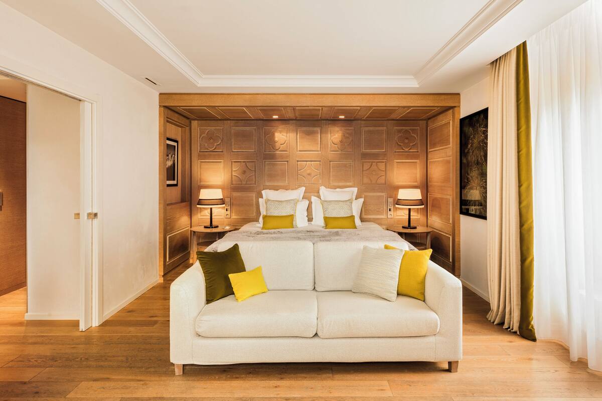 Une chambre spacieuse avec un grand lit, deux tables de chevet et un canapé blanc.