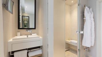 A modern bathroom with a large mirror, white sink, and glass-enclosed shower.