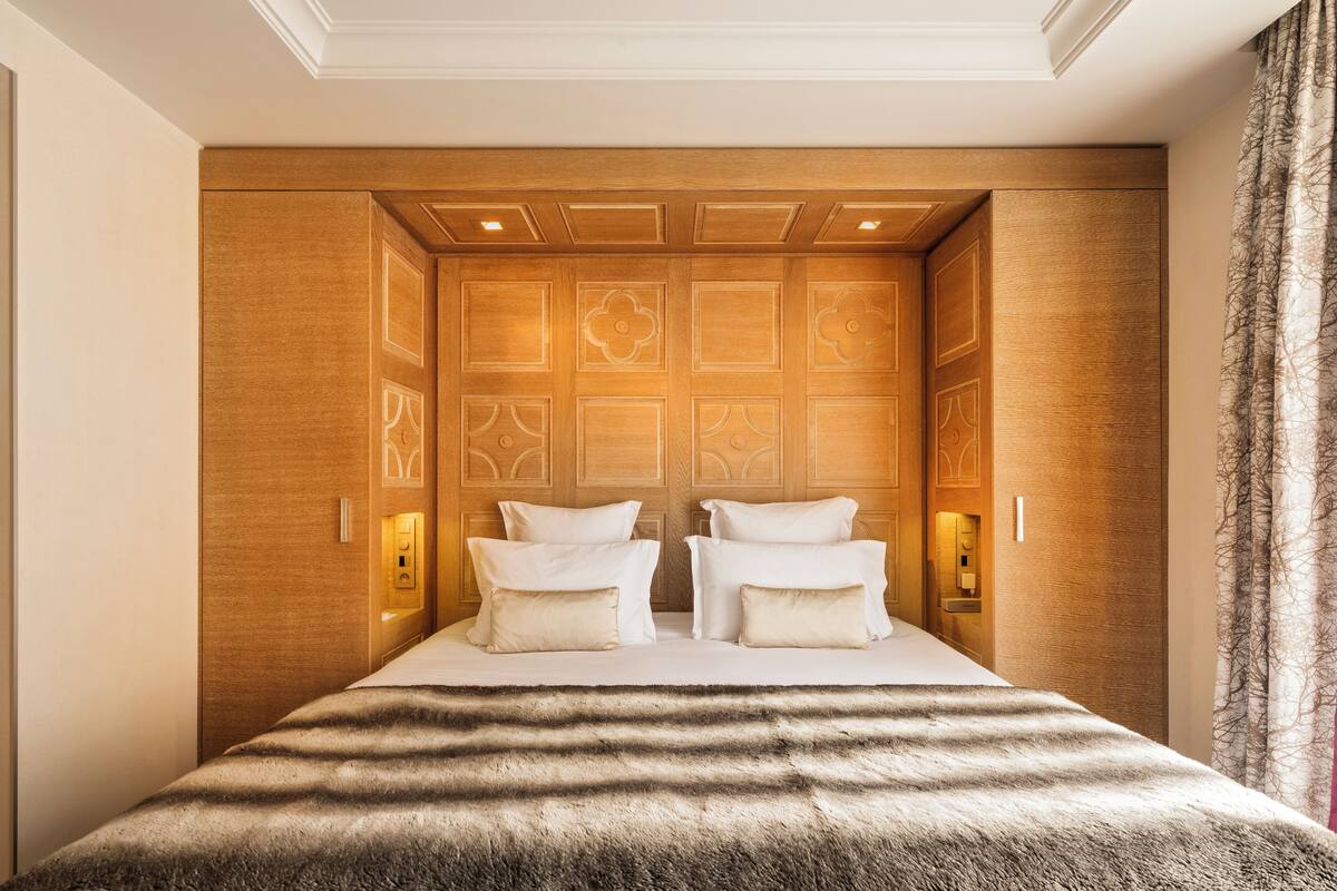 Une chambre d’hôtel avec un grand lit, des lambris en bois sur les murs et une fenêtre avec des rideaux.