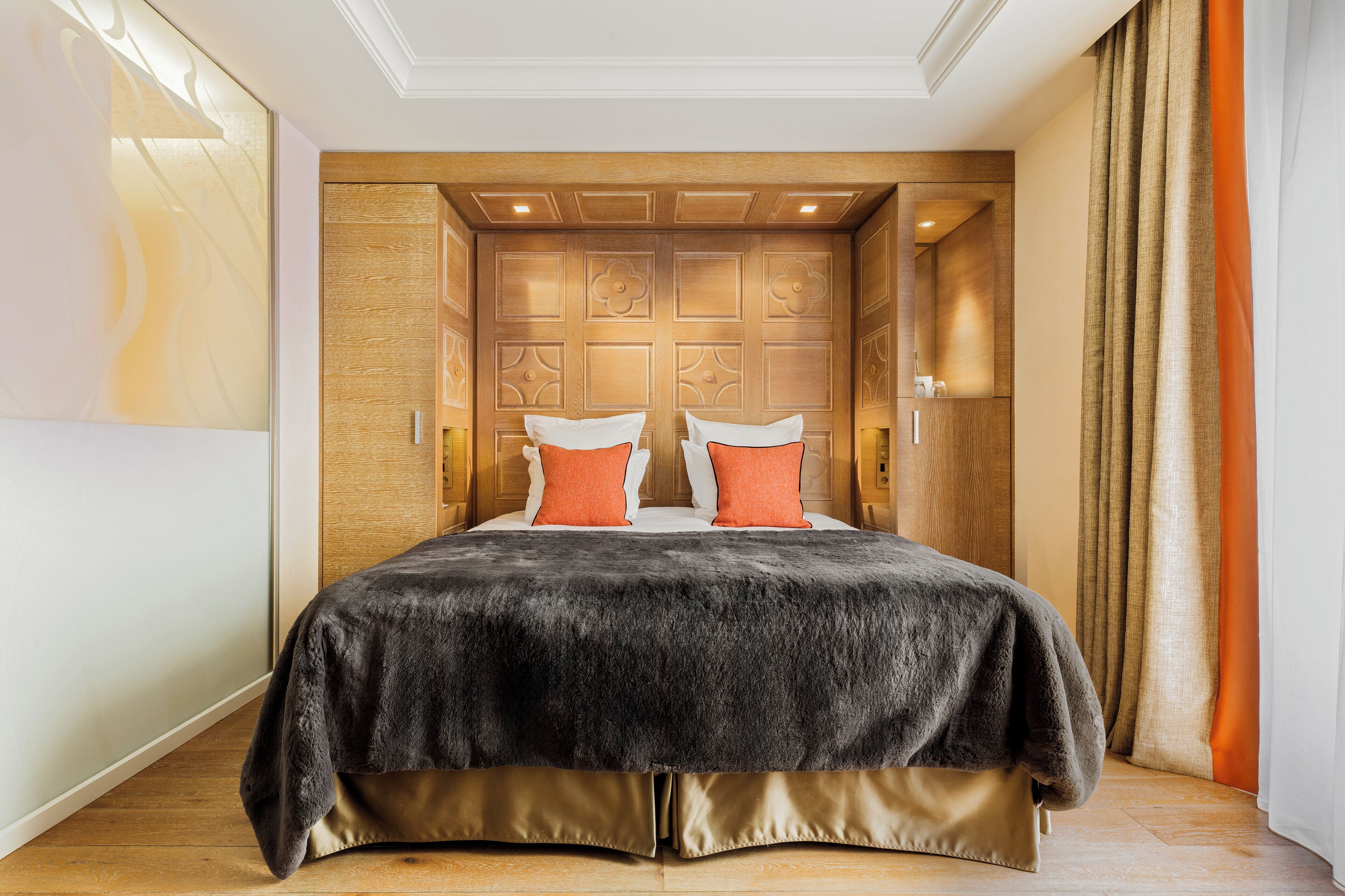 A bedroom with a large bed, wooden headboard, and a view of a cityscape.