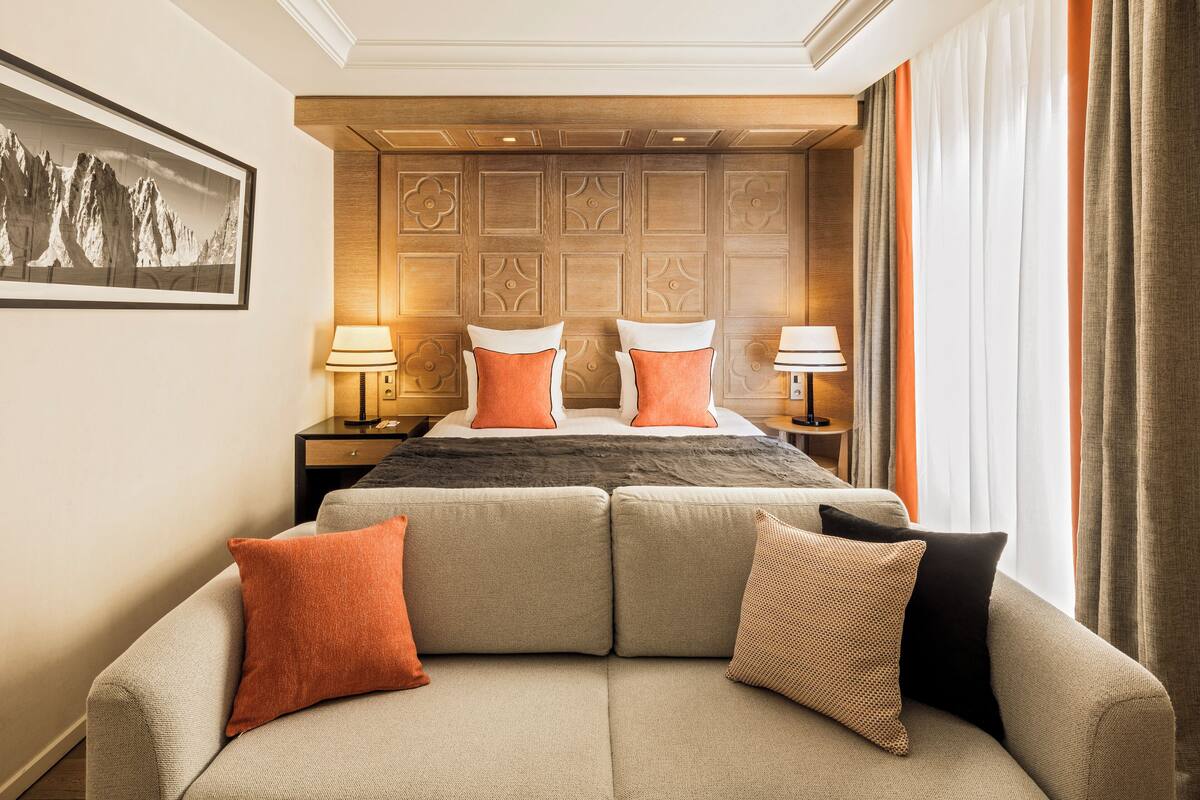 Une chambre d’hôtel avec un grand lit, un canapé et une table de chevet avec des lampes.