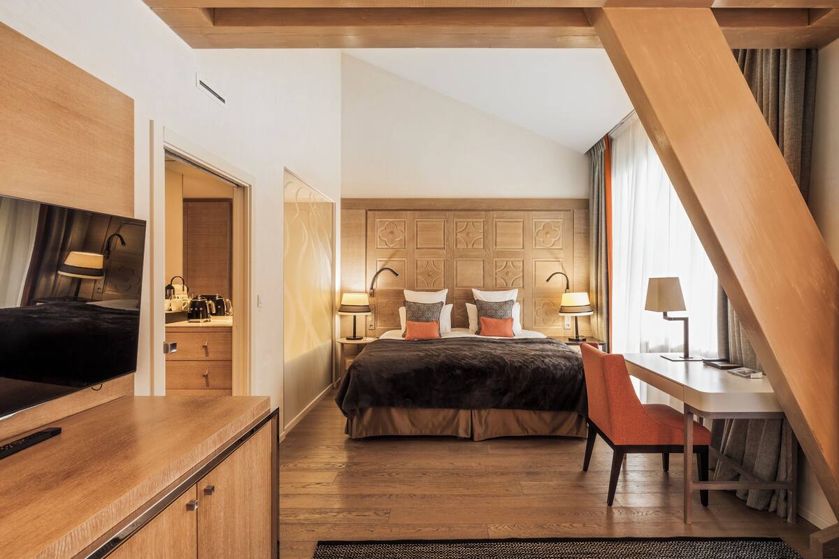 Une chambre d’hôtel moderne avec un lit en bois, un bureau et un téléviseur.