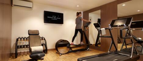 Gimnasio de hotel con cintas de correr, una bicicleta estática y una máquina de remo.