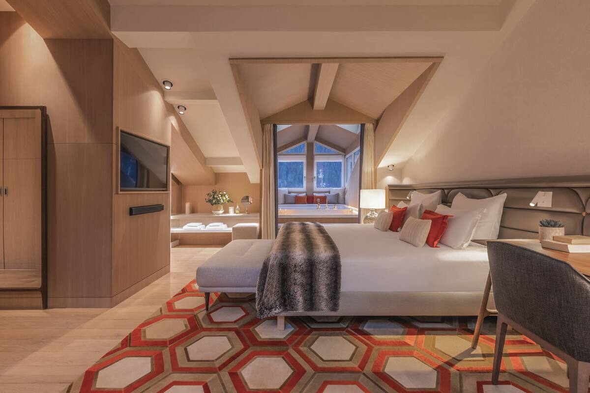 Une chambre d’hôtel moderne dotée d’un grand lit, d’une télévision, d’un bureau et offrant une vue sur l’extérieur.